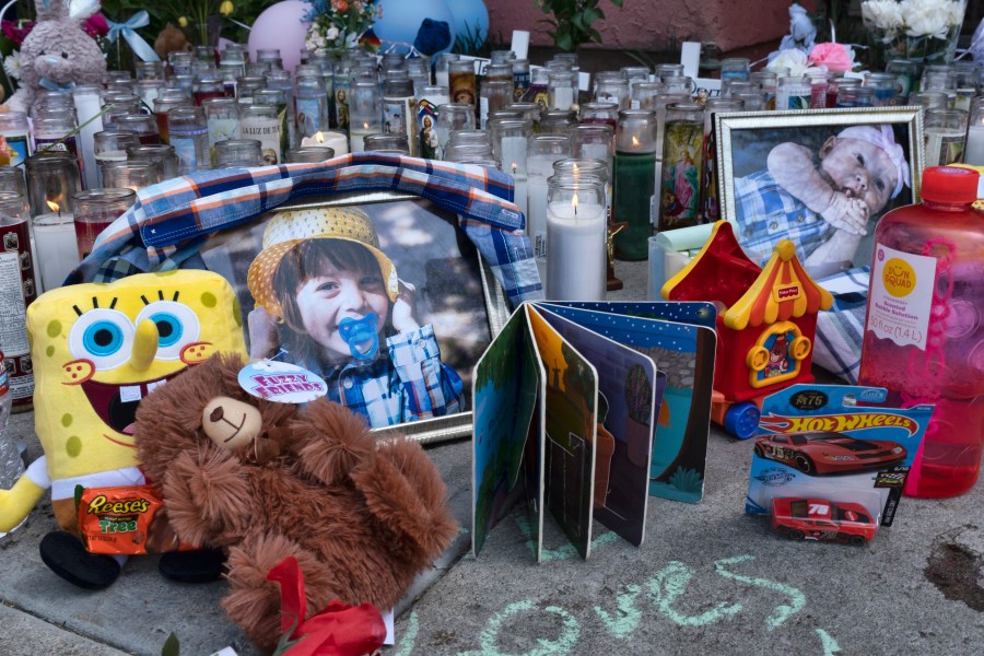 Photos, candles, flowers and balloons are placed as a memorial for three children who were killed at the Royal Villa apartments complex in the Reseda section of Los Angeles, April 12, 2021. Erik Denton, the father of the three children filed a lawsuit, Thursday, April 21, 2022, against the city and county of Los Angeles, accusing police and social workers of failing to intervene to protect his children before their deaths. (AP Photo/Richard Vogel, File)