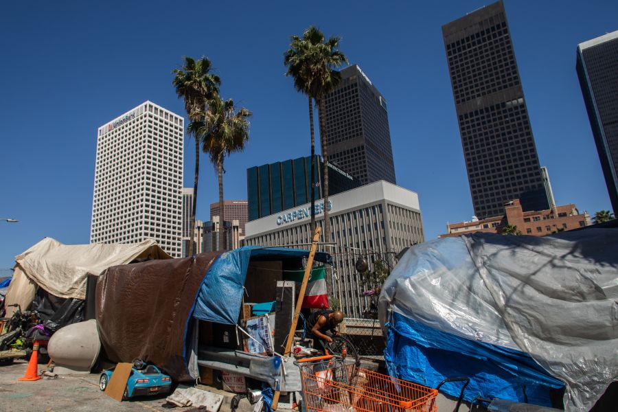 A homeless man fixes his bike outside his tent next to the 110 Freeway, during the COVID-19 pandemic in Los Angeles on May 25, 2020. (Apu Gomes/AFP via Getty Images)