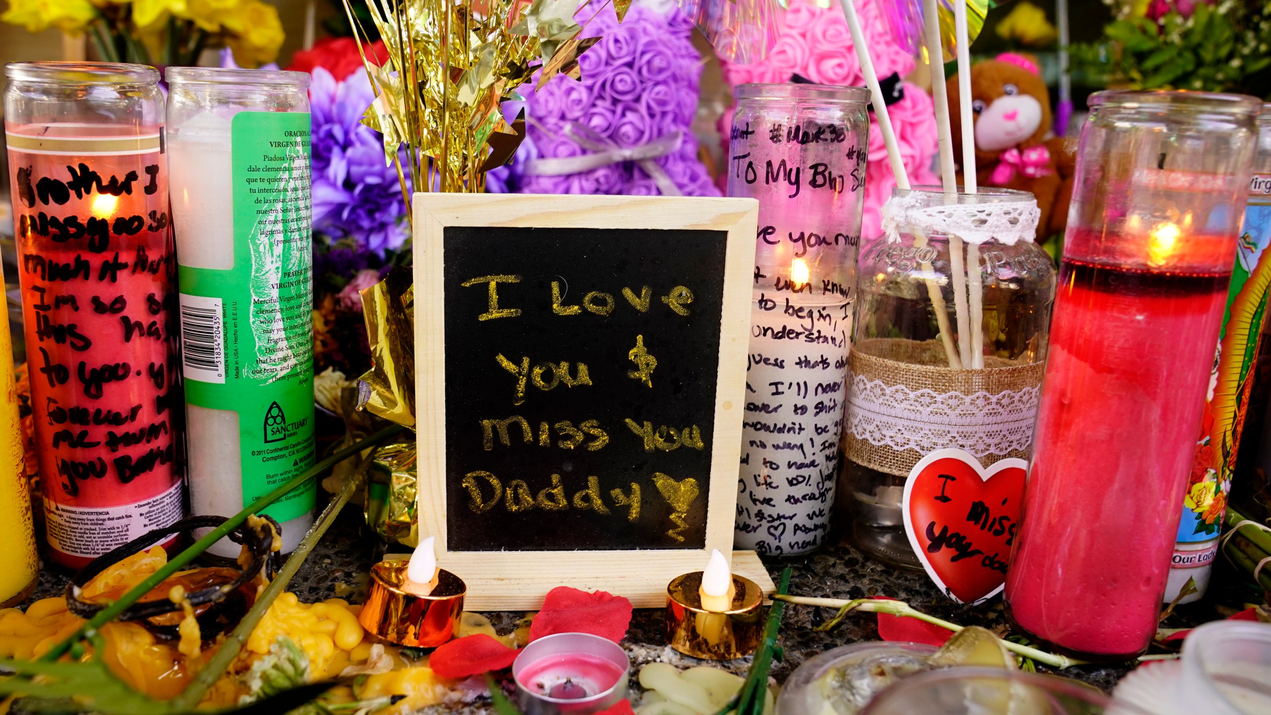 A message left for one of the victims of a recent mass shooting sits among flowers and candles at a memorial in Sacramento, Calif., Saturday, April 9, 2022. The April 3 shooting, which left six dead and 12 wounded, occurred near the state Capitol, an area that in recent years has been rattled by rising crime, protests and the economic drubbing of the pandemic. (AP Photo/Rich Pedroncelli)