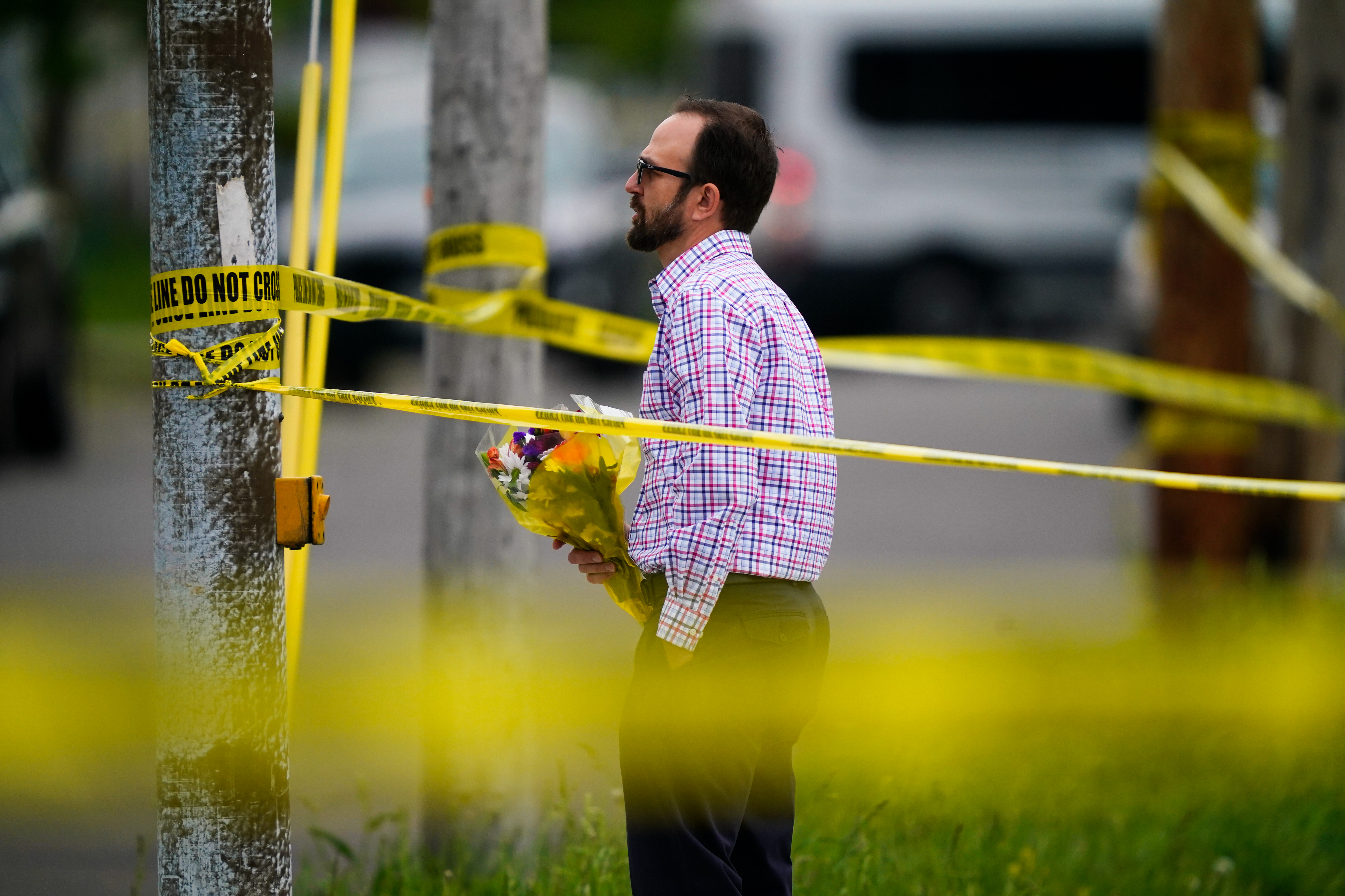 A person brings flowers to the perimeter of the scene of a shooting at a supermarket, in Buffalo, N.Y. on May 16, 2022. (Matt Rourke)