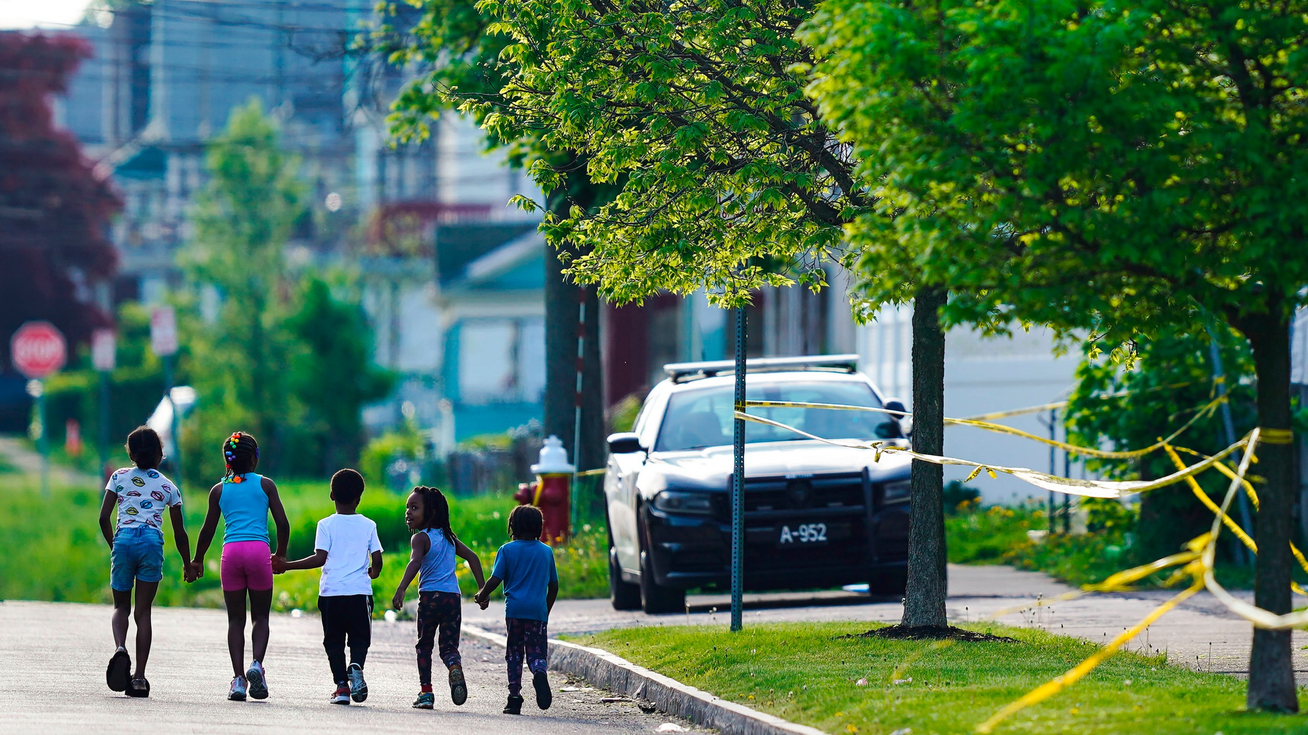 Children walk hand-in-hand near the scene of a shooting at a supermarket in Buffalo, N.Y., May 15, 2022. The shooting rampage at a Buffalo supermarket, carried out by an 18-year-old who was flagged for making a threatening comment at his high school the year before, highlights concerns over whether schools are adequately supporting and screening students. (AP Photo/Matt Rourke, File)