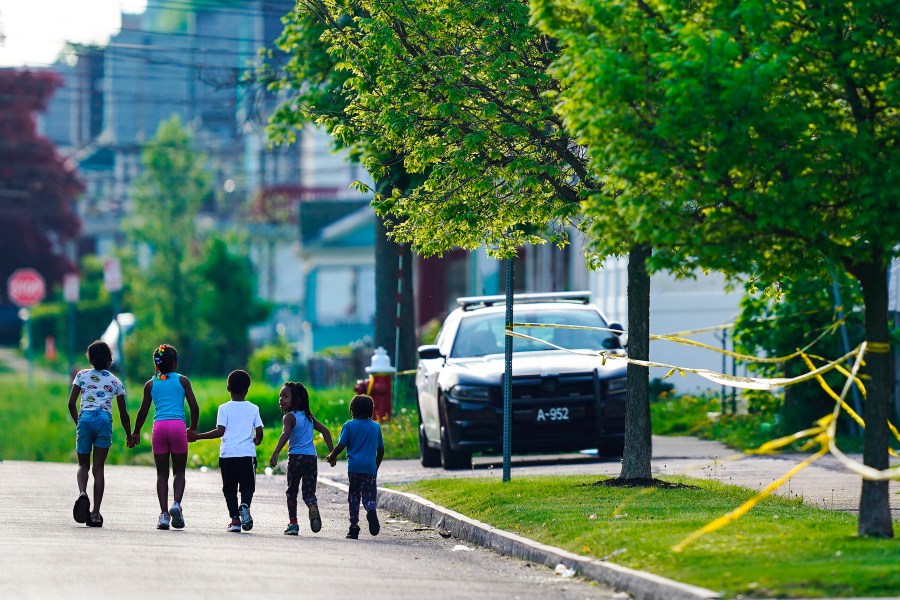 Children walk hand-in-hand near the scene of a shooting at a supermarket in Buffalo, N.Y., May 15, 2022. The shooting rampage at a Buffalo supermarket, carried out by an 18-year-old who was flagged for making a threatening comment at his high school the year before, highlights concerns over whether schools are adequately supporting and screening students. (AP Photo/Matt Rourke, File)