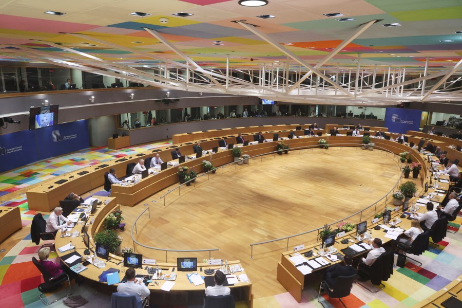 Ukrainian President Volodymyr Zelenskyy is seen on a screen, left, as addresses from Kyiv during an extraordinary meeting of EU leaders to discuss Ukraine, energy and food security at the Europa building in Brussels, Monday, May 30, 2022. (AP Photo/Olivier Matthys)