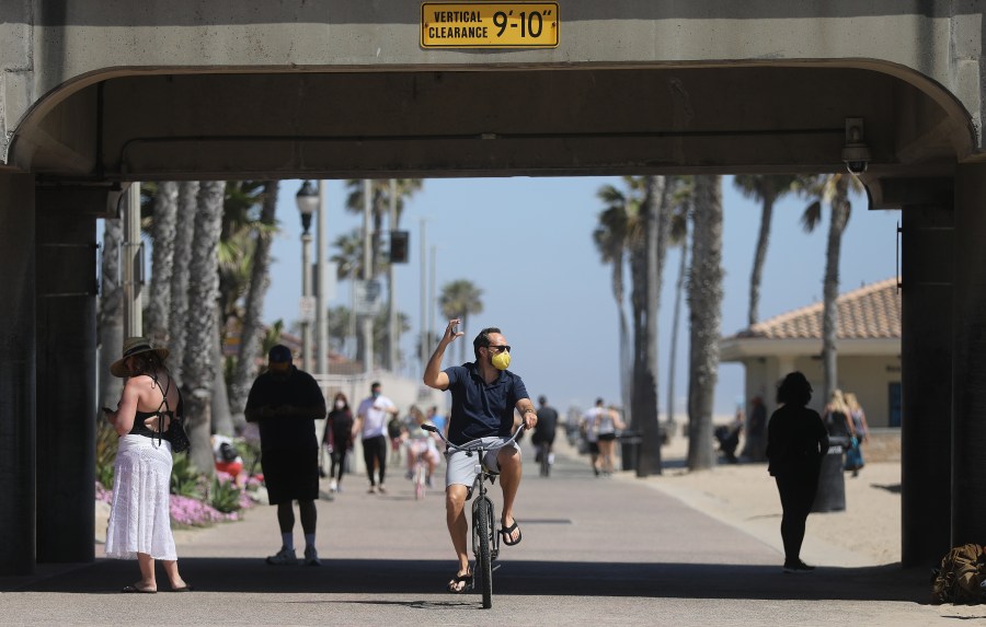 This file photo shows a man biking while wearing a face mask along Huntington Beach on April 23, 2020. (Mario Tama/Getty Images)