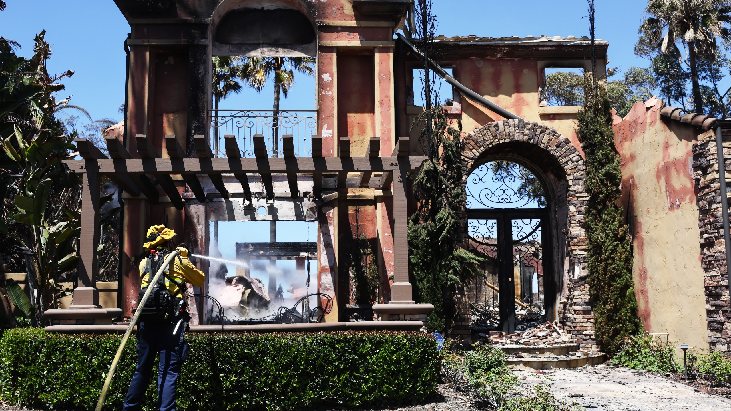 A firefighter works to put out hotspots at one of over 20 homes destroyed by the Coastal fire on May 12, 2022 in Laguna Niguel, California. (Mario Tama/Getty Images)