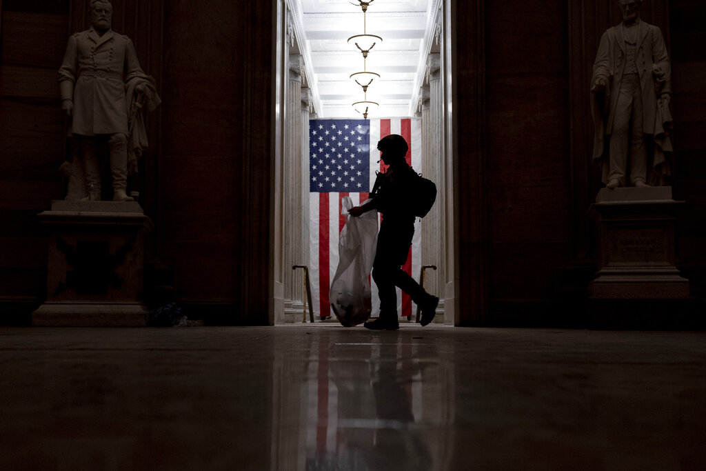 An ATF police officer cleans up debris and personal belongings that were strewn across the floor of the Rotunda in the early morning hours of Jan. 7, 2021, after violent insurrectionists stormed the Capitol in Washington. (Andrew Harnik/Associated Press)