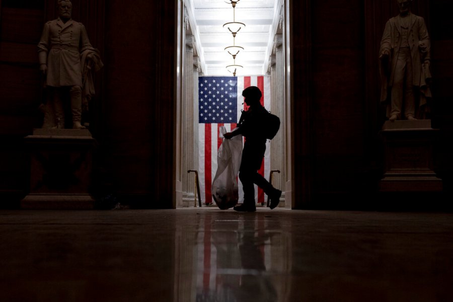 An ATF police officer cleans up debris and personal belongings that were strewn across the floor of the Rotunda in the early morning hours of Jan. 7, 2021, after violent insurrectionists stormed the Capitol in Washington. (Andrew Harnik/Associated Press)