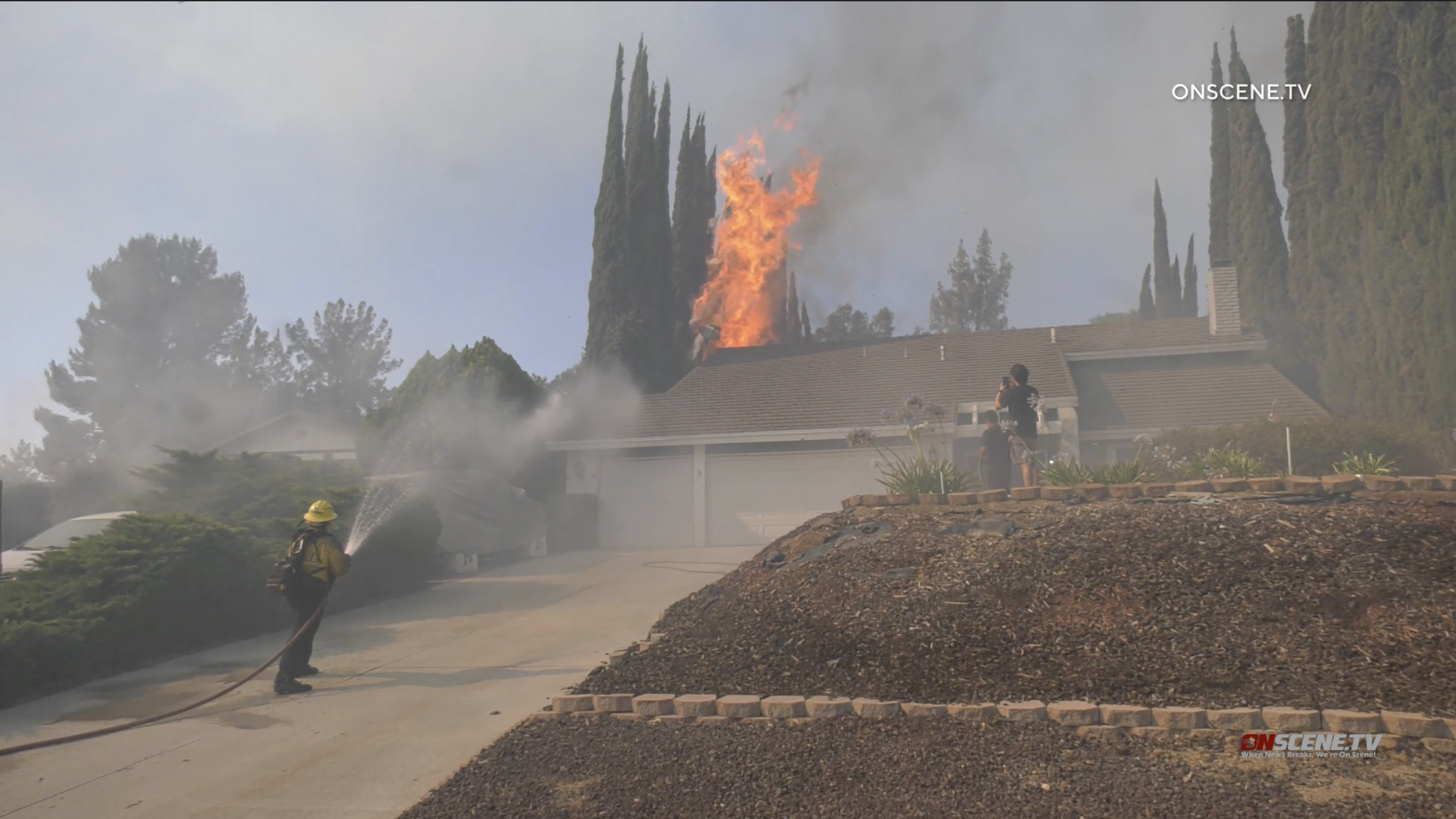 Flames burn dangeously close to a home in Jurupa Valley on Saturday, June 25, 2022 (OnScene.TV)