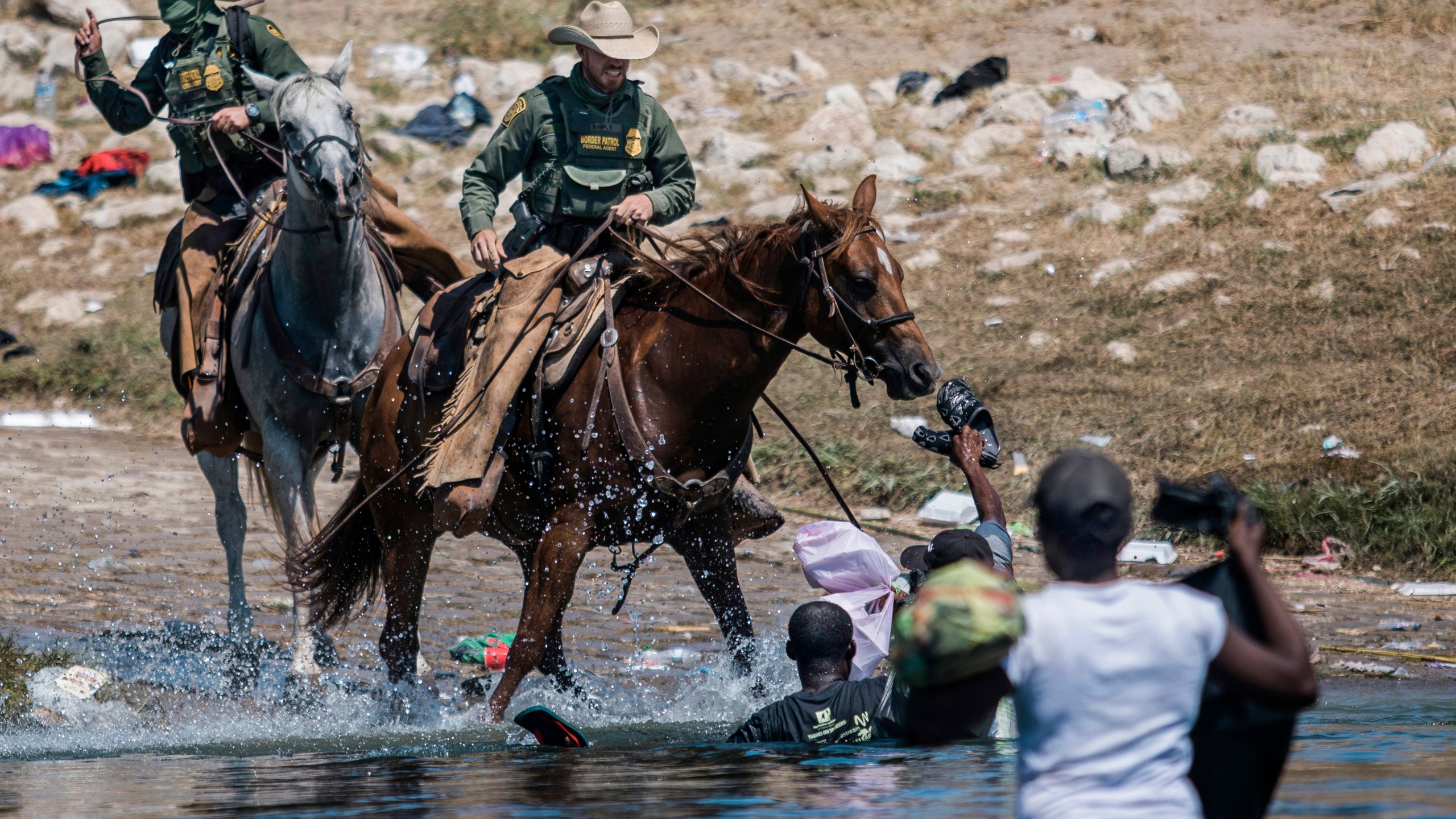 Mounted U.S. Border Patrol agents attempt to contain migrants as they cross the Rio Grande from Ciudad Acuña, Mexico, into Del Rio, Texas on Sept. 19, 2021. (Felix Marquez/Associated Press)