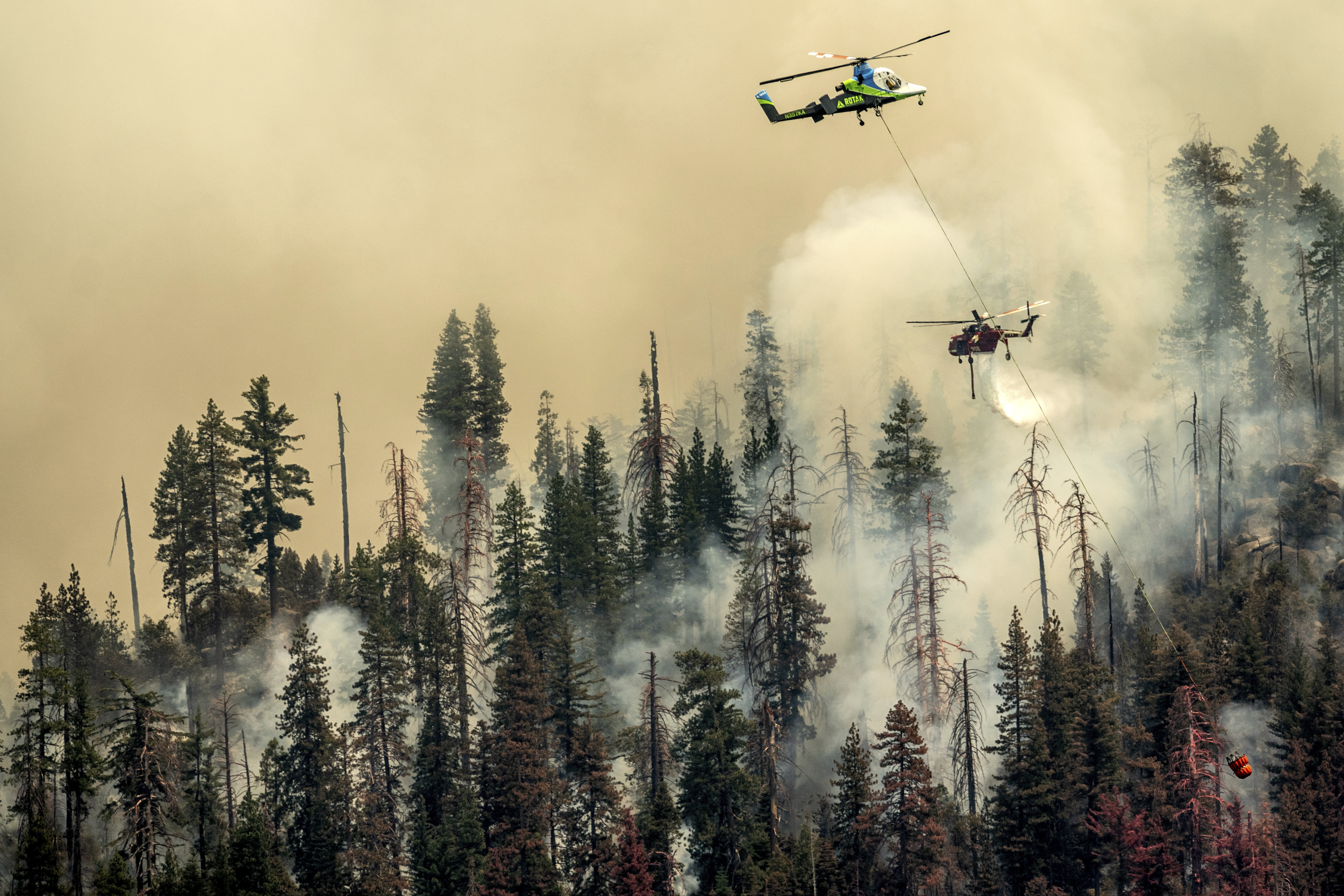 Seen from unincorporated Mariposa County, Calif., a helicopter drops water on the Washburn Fire burning in Yosemite National Park on July 9, 2022. (Noah Berger)