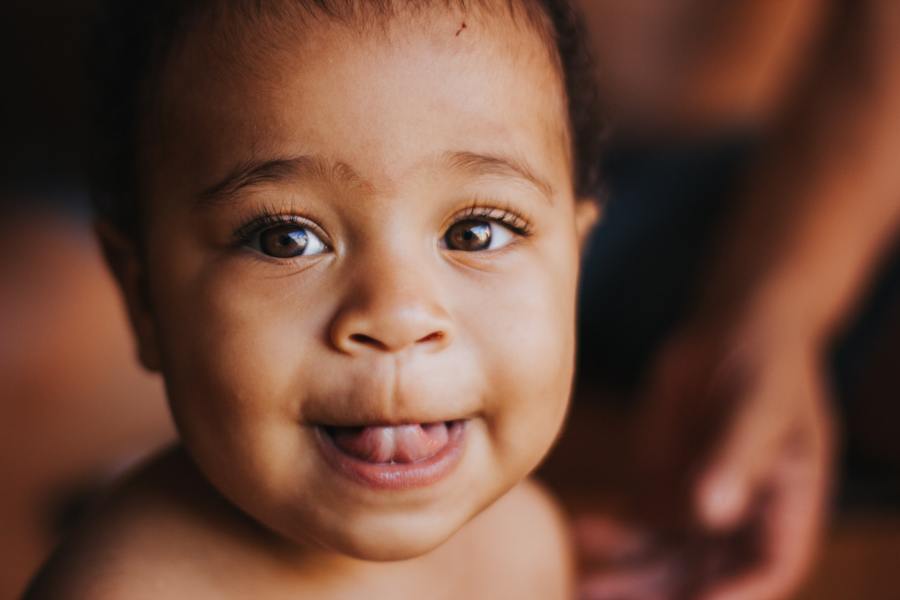 A baby smiling at the camera (Chayene Rafaela on Unsplash)