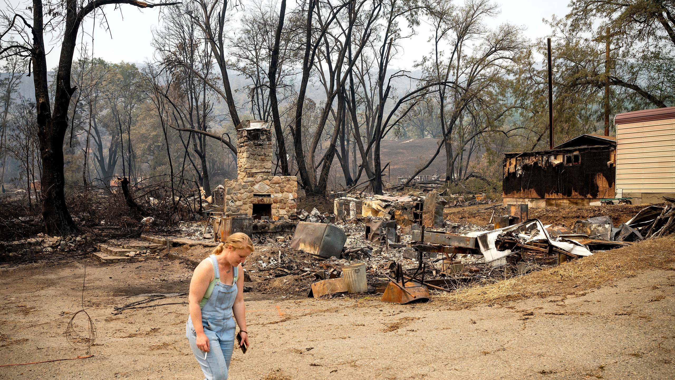 Sydney Corrales passes a lodge that burned during the McKinney Fire, Tuesday, Aug. 2, 2022, in Klamath National Forest, Calif. (AP Photo/Noah Berger)