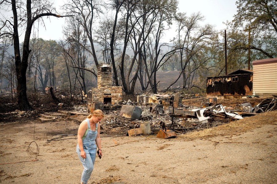 Sydney Corrales passes a lodge that burned during the McKinney Fire, Tuesday, Aug. 2, 2022, in Klamath National Forest, Calif. (AP Photo/Noah Berger)