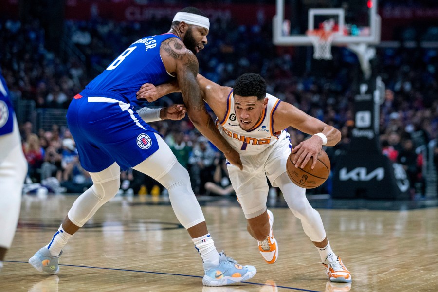 Phoenix Suns guard Devin Booker, right, drives past Los Angeles Clippers forward Marcus Morris Sr. during the first half of an NBA basketball game, Sunday, Oct. 23, 2022 in Los Angeles. (AP Photo/Alex Gallardo)