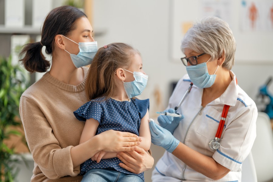 Doctor vaccinating child, kid with mother at hospital.