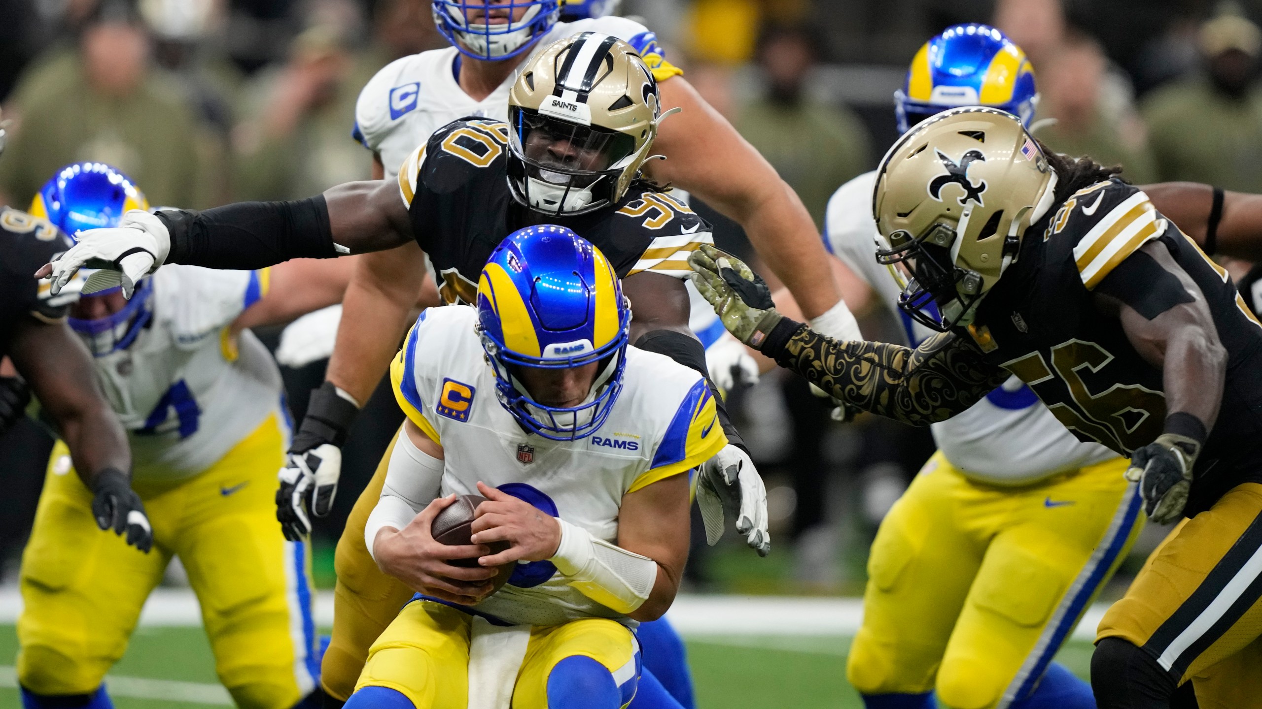 Los Angeles Rams quarterback Matthew Stafford is sacked by New Orleans Saints defenders Tanoh Kpassagnon (90) and Demario Davis (56) in the second half of an NFL football game in New Orleans on Nov. 20, 2022. (Gerald Herbert/Associated Press)