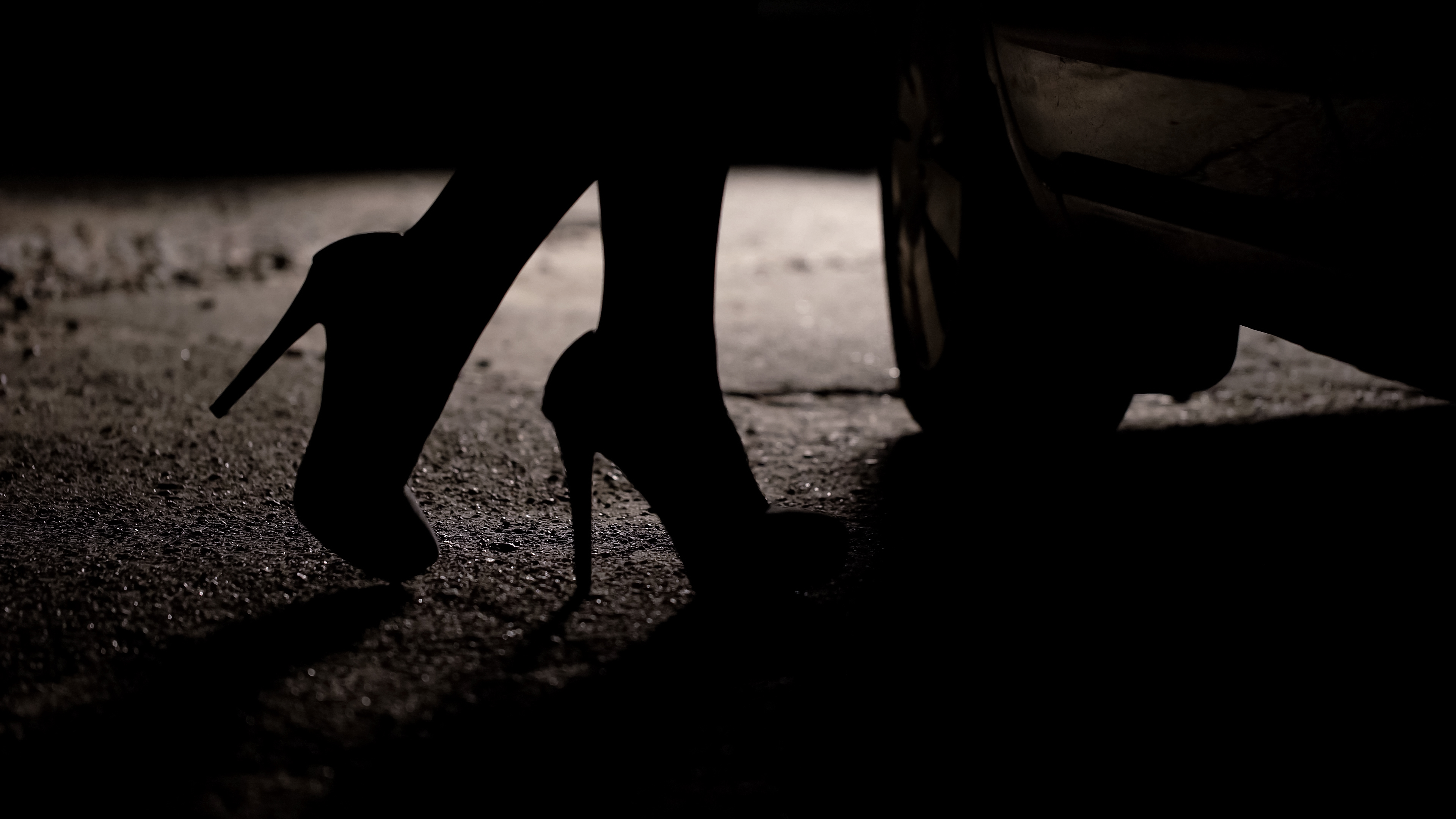 Silhouette of female legs in high heels coming to car, prostitution, sex tourism