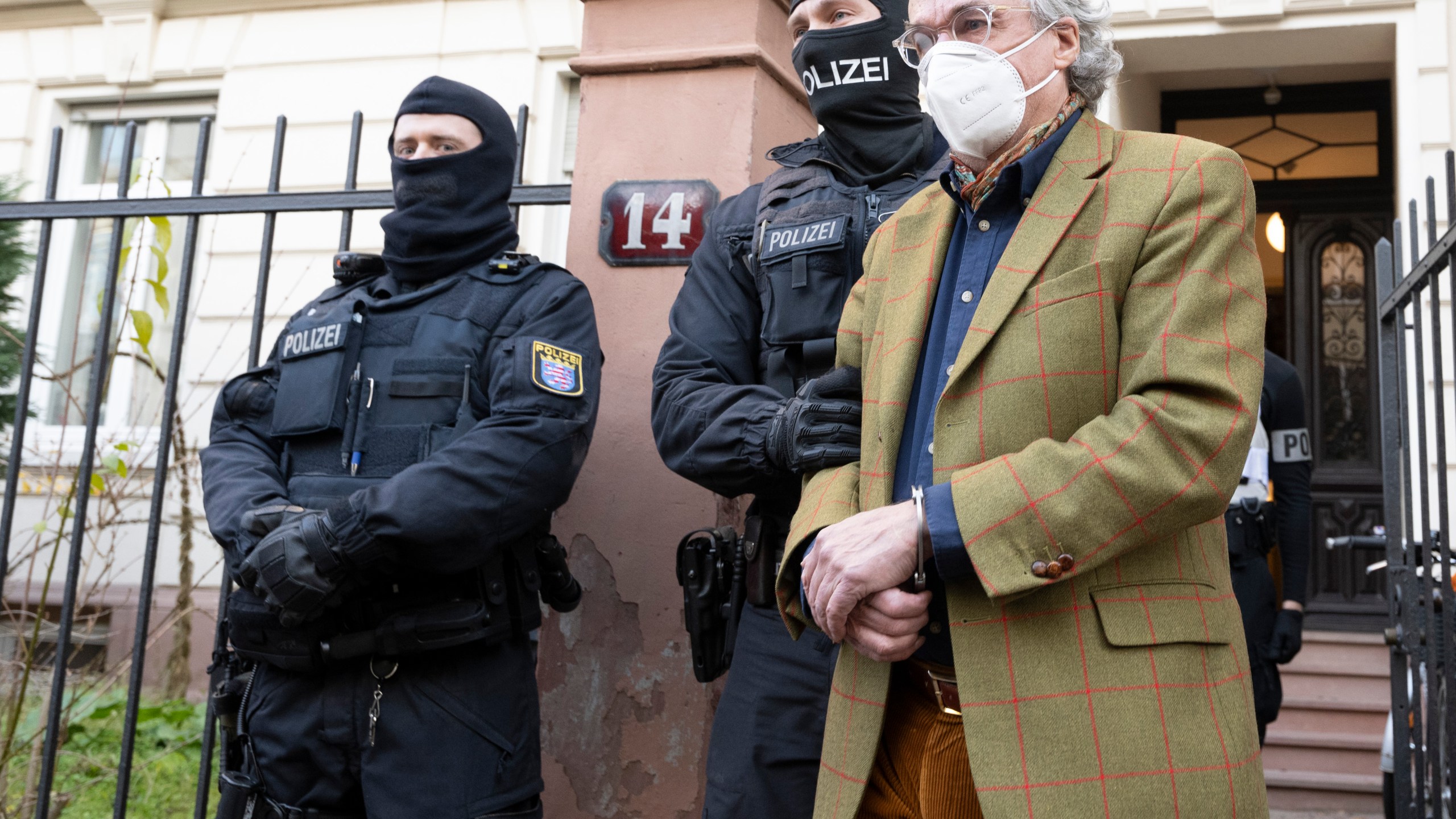 Masked police officers lead Heinrich XIII Prince Reuss, right, to a police vehicle during a raid against so-called 'Reich citizens' in Frankfurt, Germany, Wednesday, Dec. 7, 2022. Thousands of police carried out a series of raids across much of Germany on Wednesday against suspected far-right extremists who allegedly sought to overthrow the state by force. Federal prosecutors said some 3,000 officers conducted searches at 130 sites in 11 of Germany's 16 states against adherents of the so-called Reich Citizens movement. Some members of the grouping reject Germany's postwar constitution and have called for the overthrow of the government. (Boris Roessler/dpa via AP)