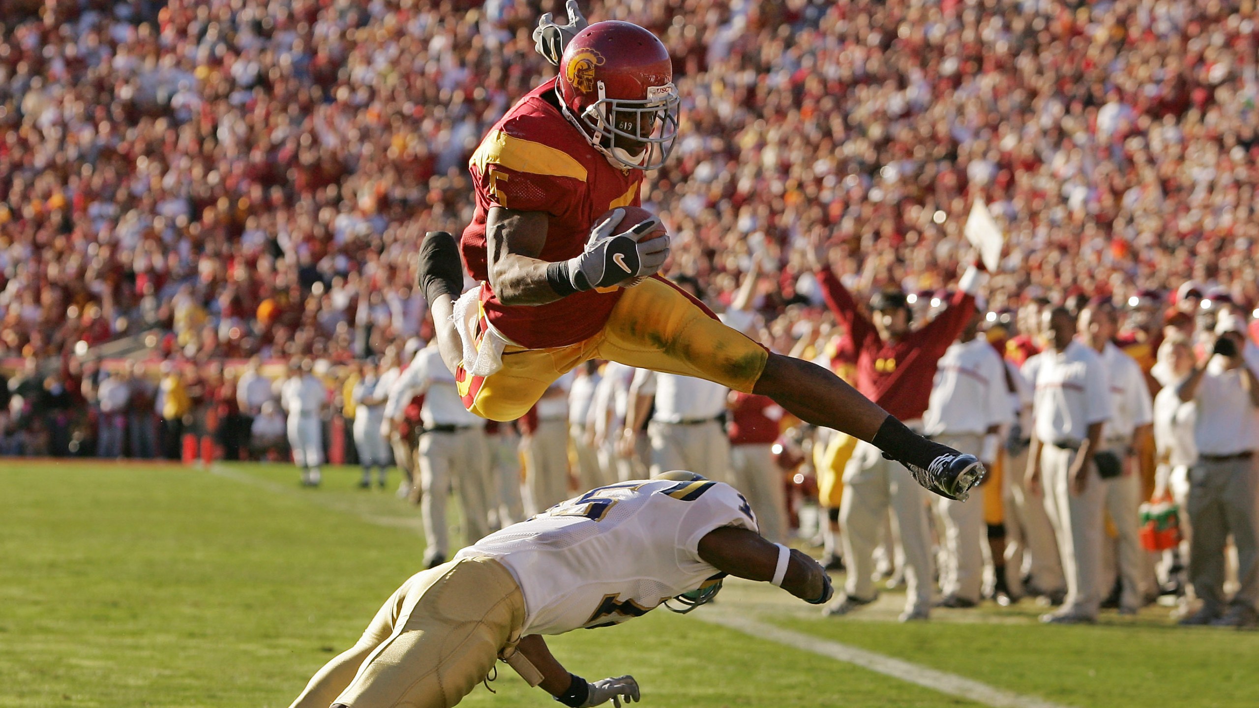 In this Dec. 3, 2005, file photo, Southern California's Reggie Bush leaps over UCLA defender Marcus Cassel as he rushes 13 yards for a touchdown in the second quarter of their game at the Los Angeles Memorial Coliseum. (AP Photo/Chris Carlson, File)