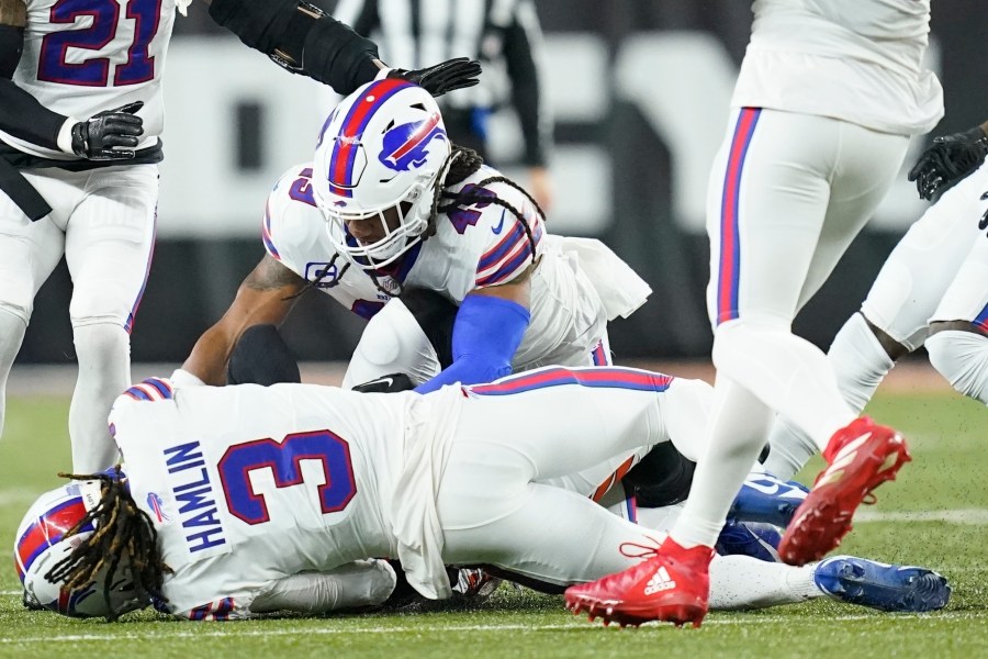 Buffalo Bills safety Damar Hamlin lies on the turf after making a tackle on Cincinnati Bengals wide receiver Tee Higgins, blocked from view, as Buffalo Bills linebacker Tremaine Edmunds assists at the end of the play during the first half of an NFL football game between the Cincinnati Bengals and the Buffalo Bills, Monday, Jan. 2, 2023, in Cincinnati. (AP Photo/Joshua A. Bickel)