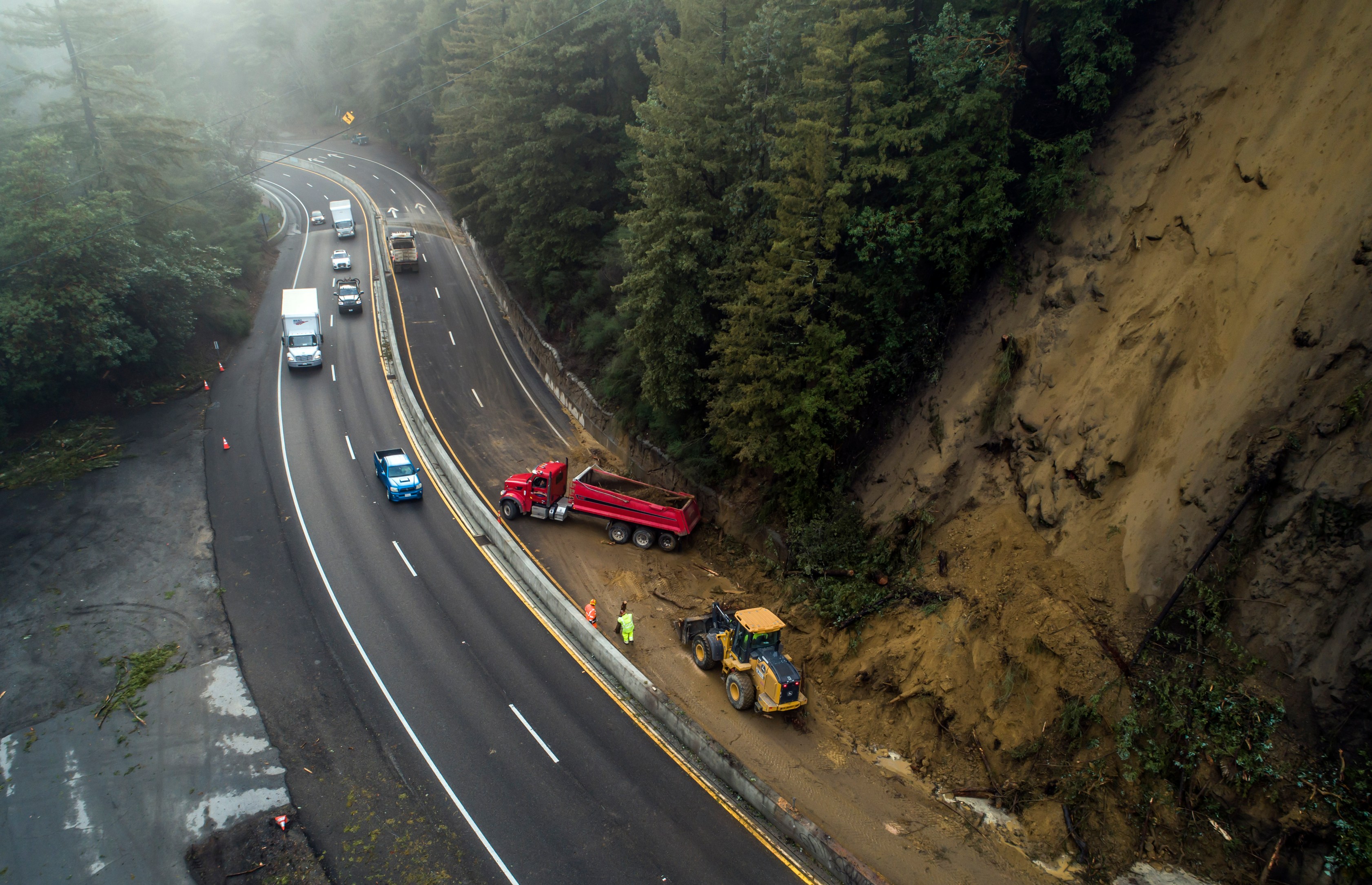 Caltrans crews work to clear a mudslide on Highway 17 that resulted from heavy rain from an atmospheric river storm in the Santa Cruz Mountains, south of Glenwood Drive in Scott's Valley, Calif. on Jan. 9, 2023. (Carlos Avila Gonzalez/San Francisco Chronicle via AP)