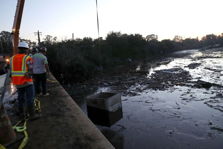 Workers drop a box that will house pumps in a flooded section of Highway 101 on January 11, 2018 in Montecito, California. 17 people have died and hundreds of homes have been destroyed or damaged after massive mudslides crashed through Montecito, California early Tuesday morning.  (Photo by Justin Sullivan/Getty Images)