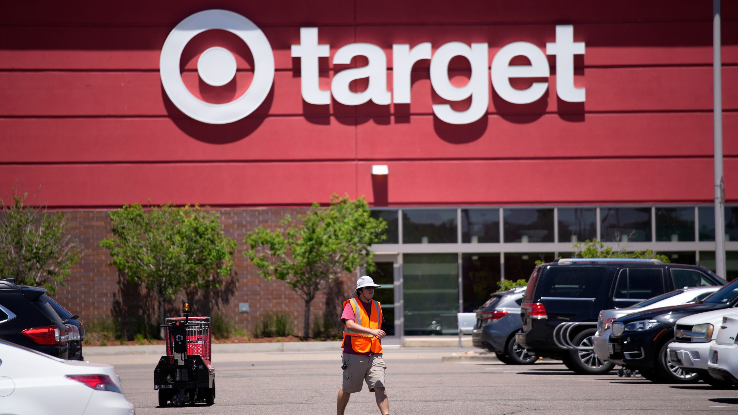 A worker collects shopping carts in the parking lot of a Target store on June 9, 2021. (AP Photo/David Zalubowski, File)