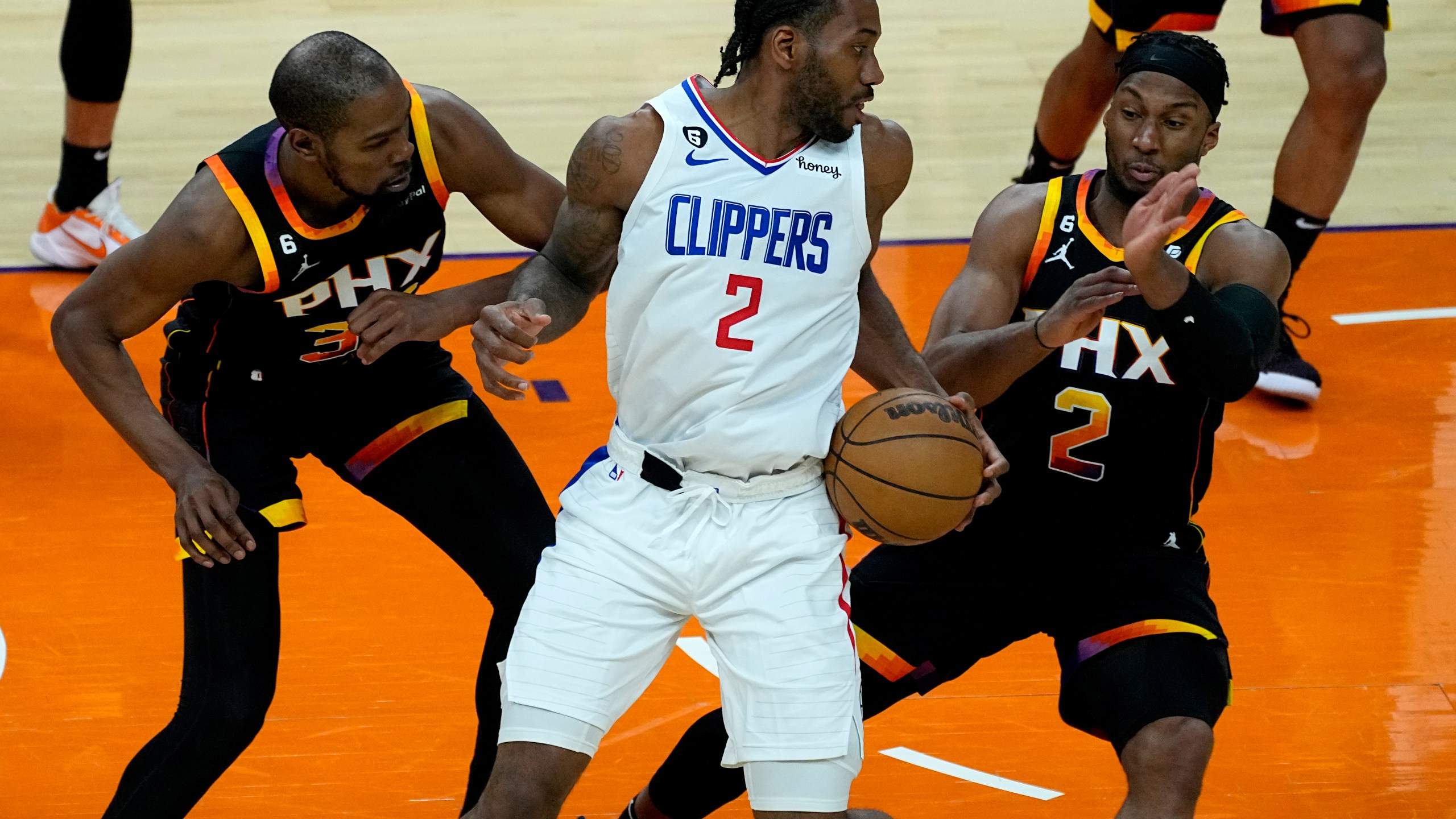 Los Angeles Clippers forward Kawhi Leonard (2) looks to pass under pressure from Phoenix Suns forward Josh Okogie (2) and forward Kevin Durant during the second half of Game 2 of a first-round NBA basketball playoff series, Tuesday, April 18, 2023, in Phoenix. (AP Photo/Matt York)