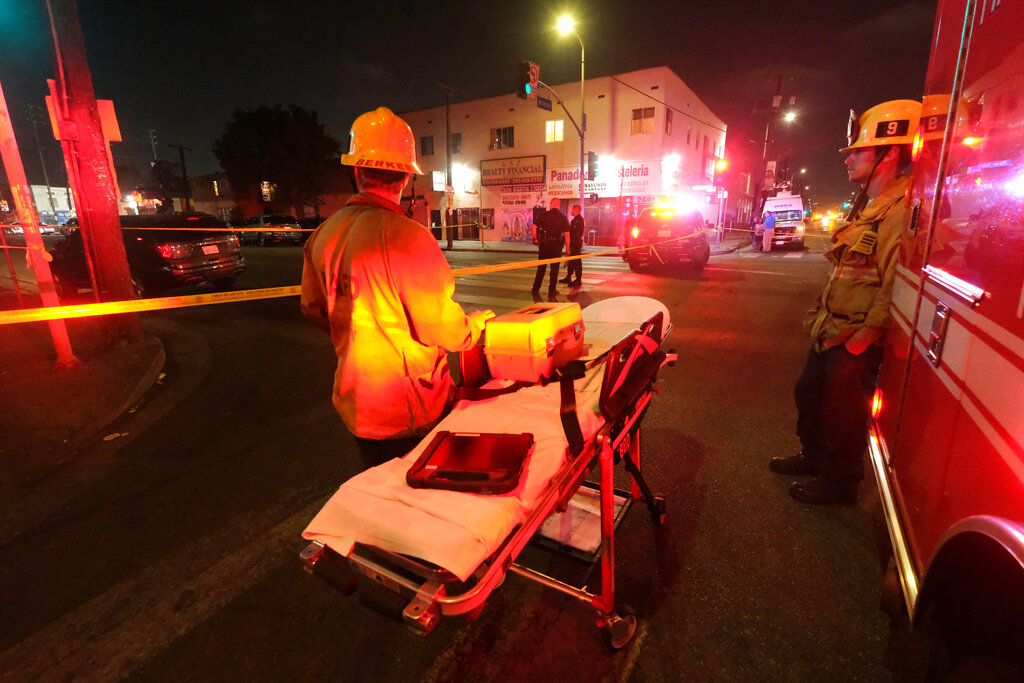 Emergency personnel stand near the scene of a fireworks explosion in Los Angeles on Wednesday, June 30, 2021. A cache of illegal fireworks seized at a South Los Angeles home exploded, damaging nearby homes and cars and causing injuries, authorities said. (AP Photo/Ringo H.W. Chiu)