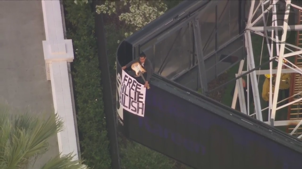 A man was seen climbing the KTLA 5 radio tower in Hollywood while holding a sign that read, “Free Billie Eilish” as authorities worked to remove him on April 25, 2023. (KTLA)