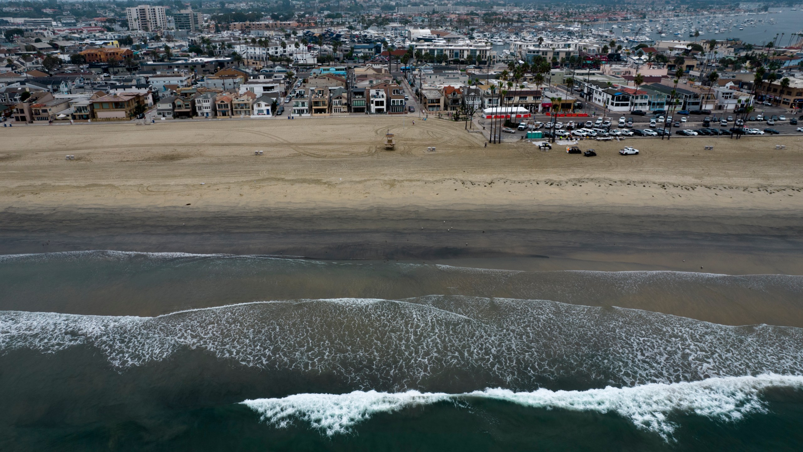 This aerial image taken with a drone shows the closed beach after oil washed up in Newport Beach, Calif., on Oct. 7, 2021. An offshore pipeline involved in a 2021 oil spill that fouled Southern California beaches is being put back in service, the operator said. Amplify Energy Corp. said Monday, April 11, 2023, that it received approval from federal regulatory agencies to restart operations and last weekend began the process of filling the pipeline, which is expected to take about two weeks. (AP Photo/Ringo H.W. Chiu, File)