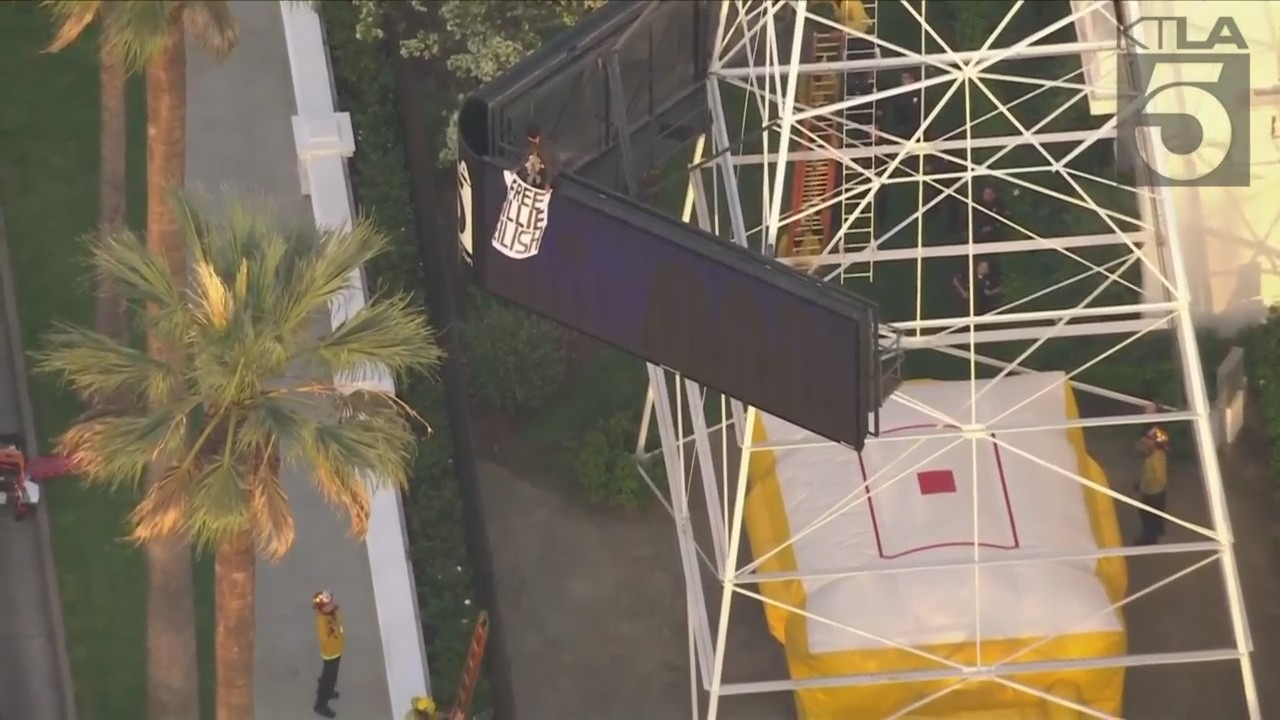 A man was seen climbing the KTLA 5 radio tower in Hollywood while holding a sign that read, “Free Billie Eilish” as authorities worked to remove him on April 25, 2023. (KTLA)