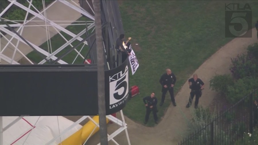 A man was seen climbing the KTLA 5 radio tower in Hollywood while holding a sign that read, “Free Billie Eilish” as authorities worked to remove him on April 25, 2023. (KTLA)