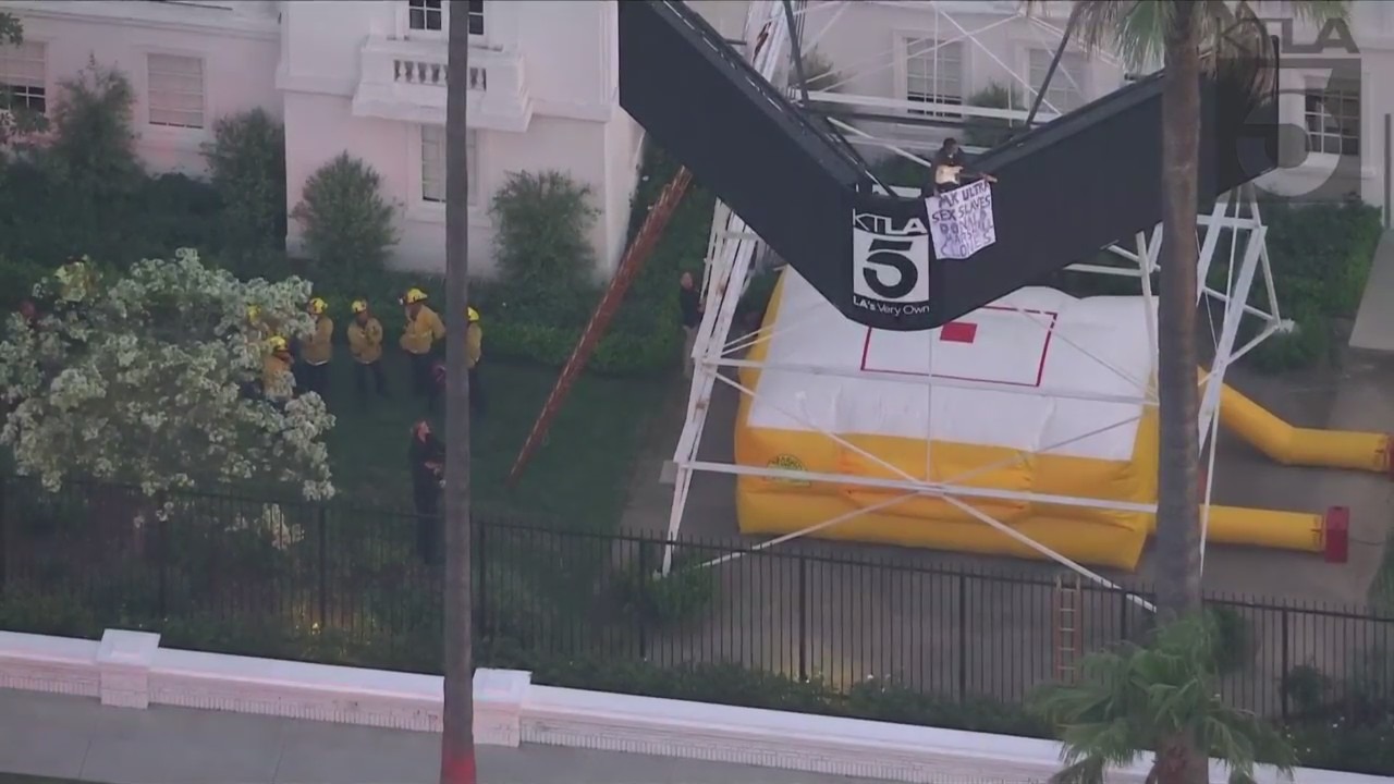 A man was seen climbing the KTLA 5 radio tower in Hollywood while holding a sign that read, “Free Billie Eilish” as authorities worked to remove him on April 25, 2023. (KTLA)