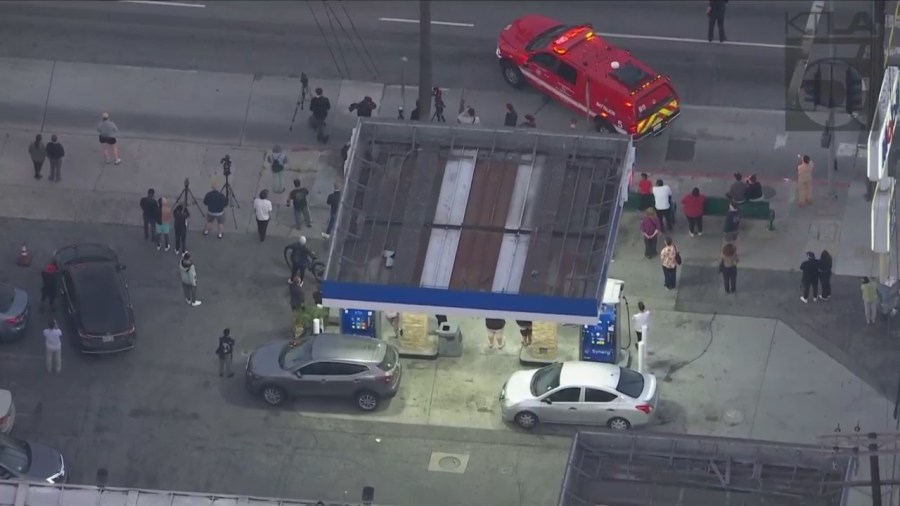 Bystanders watch as a man climbed the KTLA 5 radio tower in Hollywood while holding a sign that read, “Free Billie Eilish” on April 25, 2023. (KTLA)