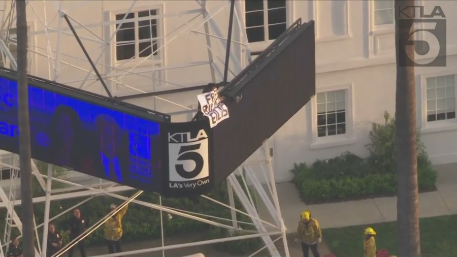 A man was seen climbing the KTLA 5 radio tower in Hollywood while holding a sign that read, “Free Billie Eilish” as authorities worked to remove him on April 25, 2023. (KTLA)