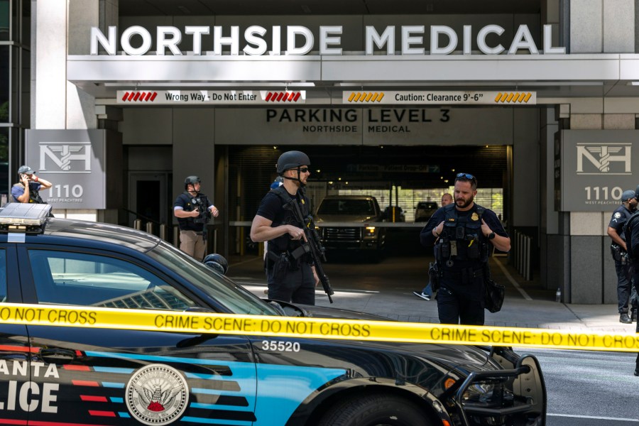 Law enforcement officers stand Northside Hospital Midtown medical office building, where five people were shot, Wednesday, May 3, 2023, in Atlanta. Authorities swarmed the city’s bustling midtown neighborhood in search of the 24-year-old suspect. (Arvin Temkar/Atlanta Journal-Constitution via AP)