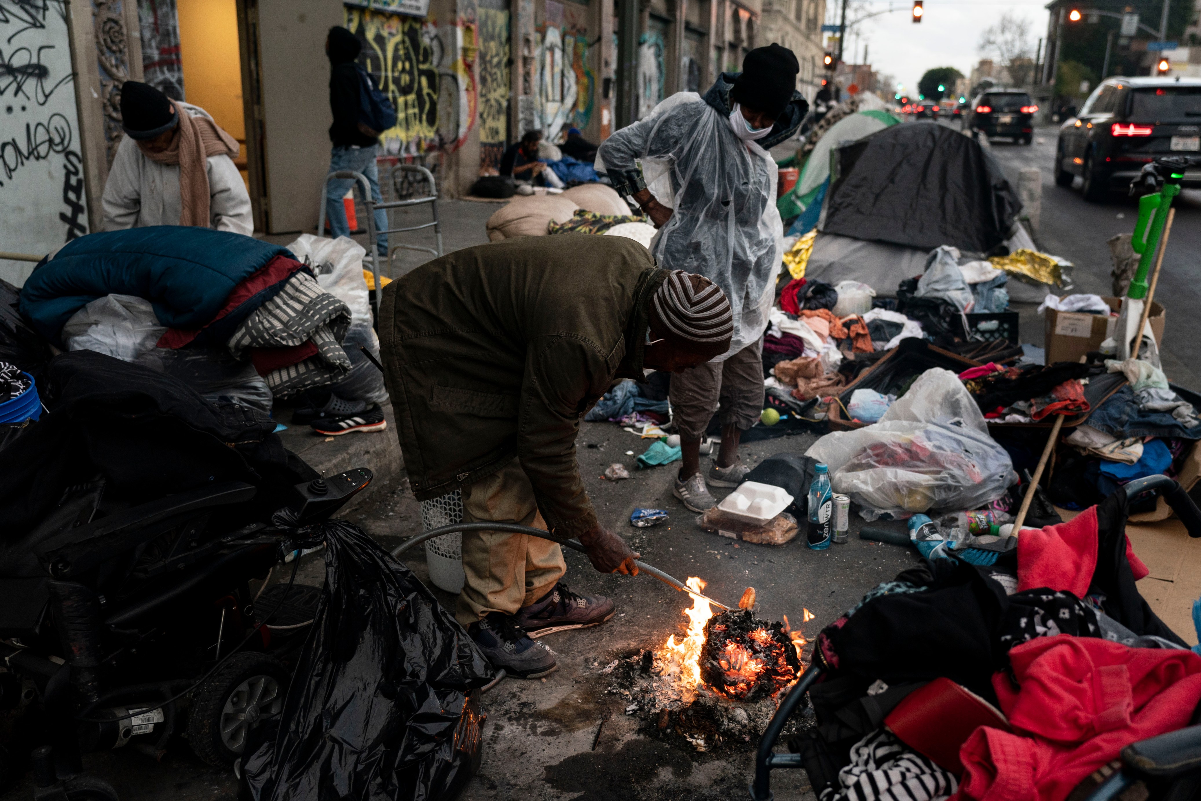 FILE - Robert Mason, a 56-year-old homeless man, warms up a piece of doughnut over a bonfire he set to keep himself warm on Skid Row in Los Angeles, Tuesday, Feb. 14, 2023. Five major U.S. cities and the state of California will receive federal help to get unsheltered residents into permanent housing under a new plan announced Thursday, May 18, 2023, as part of the Biden administration's larger goal to reduce homelessness 25% by 2025. (AP Photo/Jae C. Hong, File)