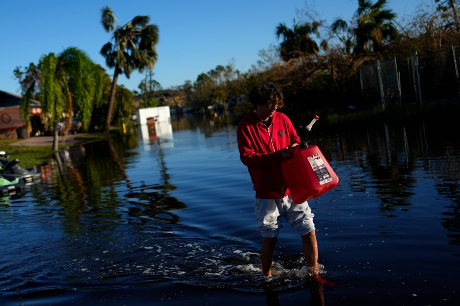 FILE - Jose Cruz, 13, carries an empty Jerrycan through receding flood waters outside his house as his family heads out to look for supplies, three days after the passage of Hurricane Ian, in Fort Myers, Fla., Oct. 1, 2022. After months of gradually warming sea surface temperatures in the tropical Pacific Ocean, NOAA officially issued an El Nino advisory Thursday, June 8, 2023, and stated that this one might be different than the others. (AP Photo/Rebecca Blackwell, File)