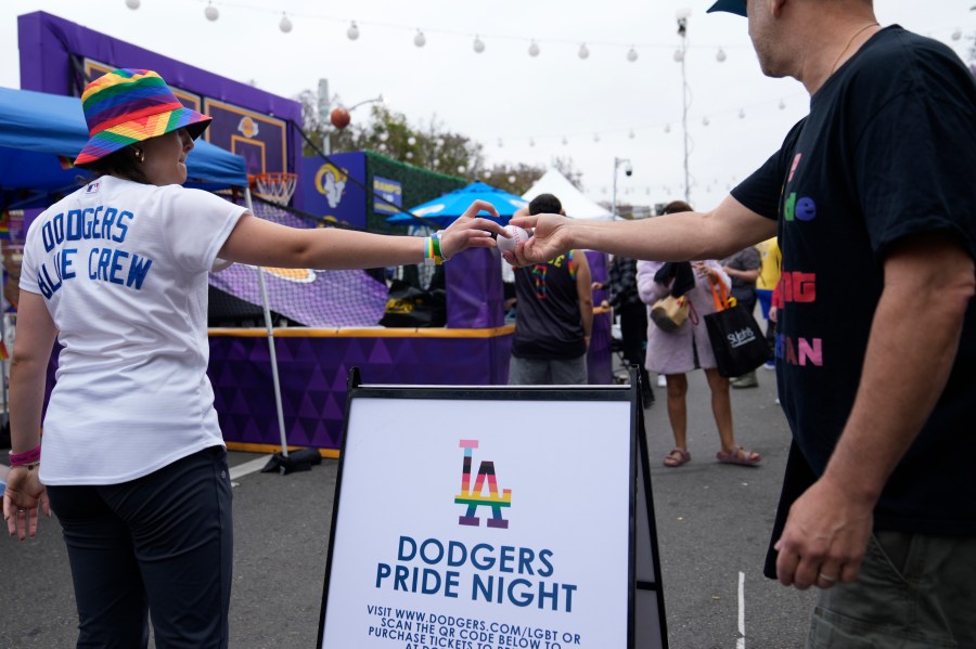 FILE - A Los Angeles Dodgers Pride promoter gives a ball to a participant at the WeHo Pride Parade in West Hollywood, Calif., on Sunday, June 4, 2023. Under a barrage of criticism from some conservative Catholics, the team rescinded an invitation to a satirical LGBTQ+ group called the Sisters of Perpetual Indulgence to be honored at the 2023 Pride Night. A week later, after a vehement backlash from LGBTQ+ groups and their allies, the Dodgers reversed course — re-inviting the Sisters’ Los Angeles chapter to be honored for its charity work and apologizing to the LGBTQ+ community. (AP Photo/Damian Dovarganes, File)