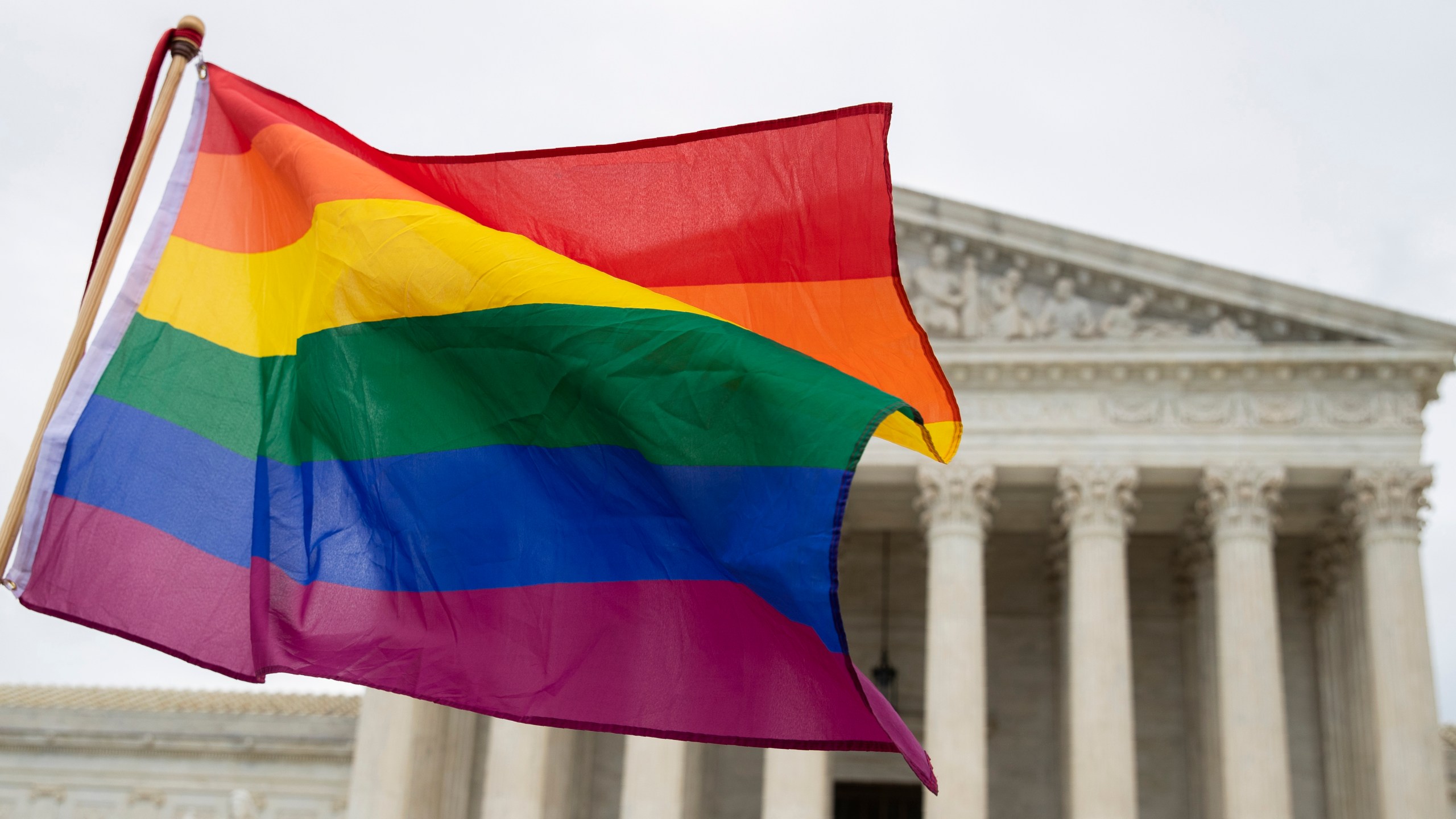 FILE - Supporters wave a pride flag in front of the U.S. Supreme Court, Oct. 8, 2019, in Washington. The Supreme Court is getting ready to decide some of its biggest cases of the term, including the case involving a Christian graphic artist from Colorado who wants to begin designing wedding websites but objects to making wedding websites for same-sex couples. (AP Photo/Manuel Balce Ceneta, File)