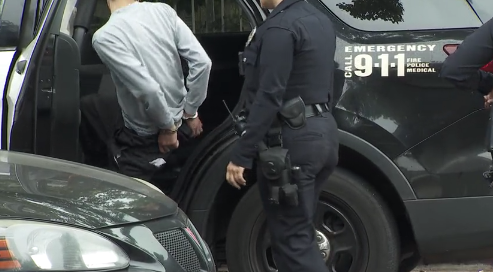 One of two people is seen being taken into custody in connection with an armed robbery in North Hills on June 19, 2023. (KTLA)