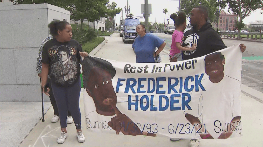 Loved ones hold up a sign honoring Frederick Holder on June 22, 2023. (KTLA)