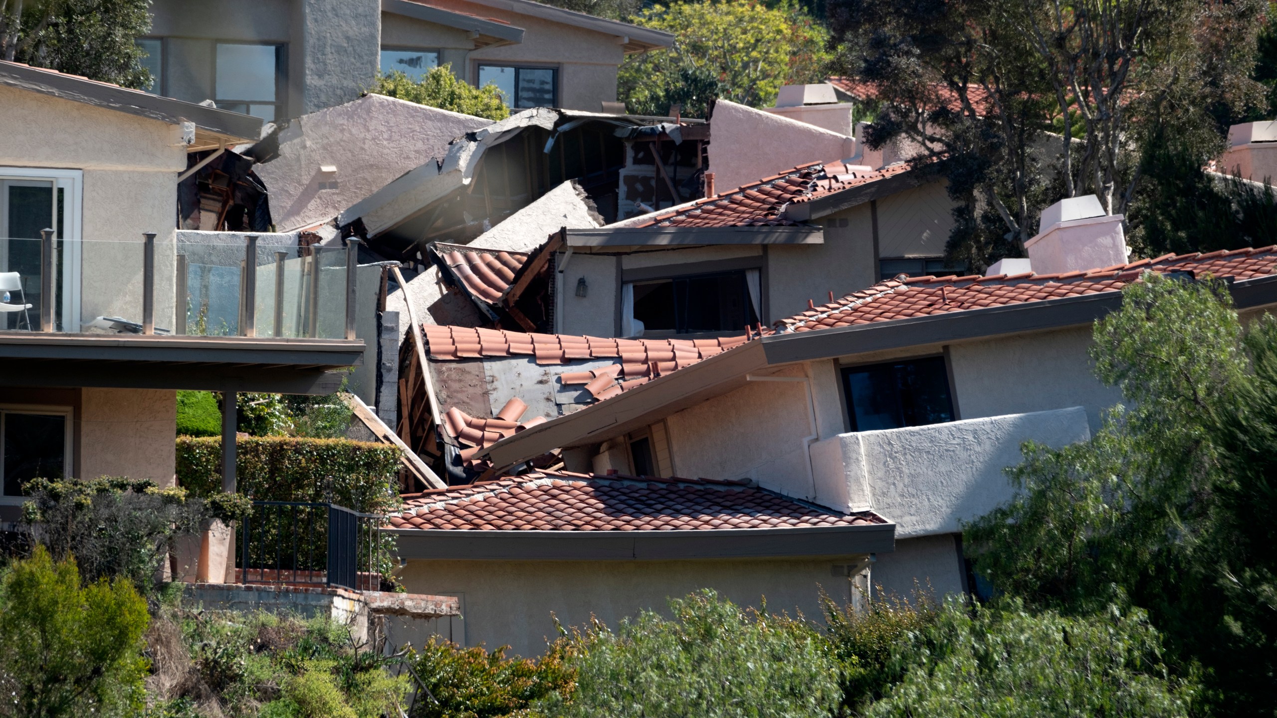 Damaged homes are torn apart by earth movement in the Los Angeles County city of Rolling Hills Estates, Calif., on Monday, July 10, 2023. The dozen homes torn apart were hastily evacuated by firefighters Saturday when cracks began appearing in structures and the ground. (AP Photo/Richard Vogel)