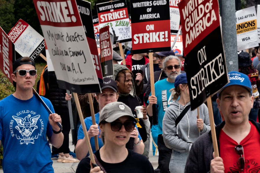 FILE -Picketers pass near a studio entrance during a Writers Guild rally outside Warner Bros. Studios, Wednesday, May 24, 2023, in Burbank, Calif. As a strike drags on, about 1,000 Hollywood writers and their supporters have marched and rallied in Los Angeles for a new contract with studios that includes the payment guarantees and job security they say they deserve. Speakers at Wednesday's event on June 21, emphasized the solidarity the Writers Guild of America has received from other unions. (AP Photo/Richard Vogel, File)