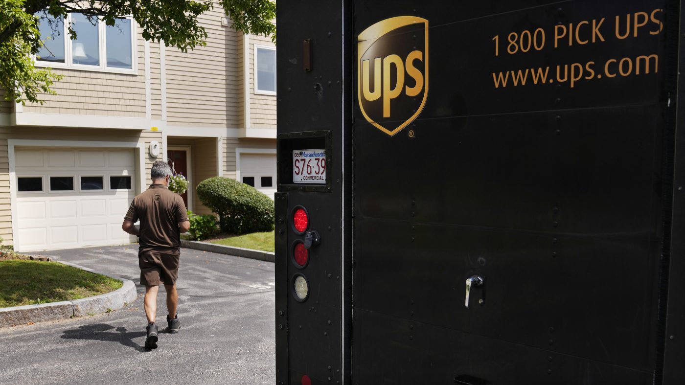 United Parcel Service deliveryman walks through a neighborhood while carrying packages to a home.