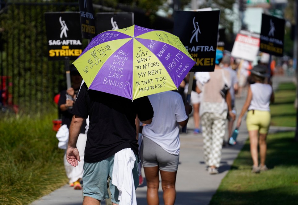 SAG-AFTRA member Chris Paseka walks on a picket line outside Netflix studios on Tuesday, July 25, 2023, in Los Angeles. The actors strike comes more than two months after screenwriters began striking in their bid to get better pay and working conditions. (AP Photo/Chris Pizzello)