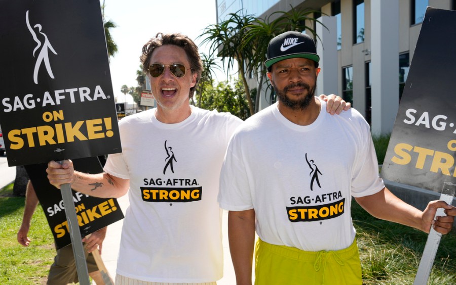 Zach Braff, left, and Donald Faison walk on a picket line outside Netflix studios on Tuesday, July 25, 2023, in Los Angeles. The actors strike comes more than two months after screenwriters began striking in their bid to get better pay and working conditions. (AP Photo/Chris Pizzello)