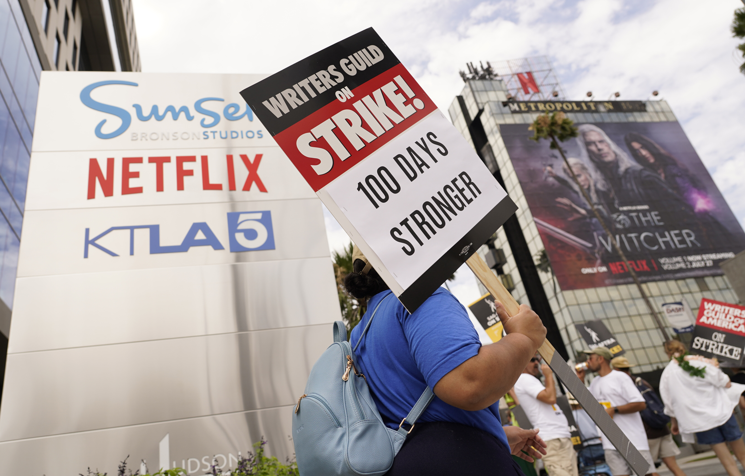 A picketer carries a sign outside Netflix studios on Wednesday, Aug. 9, 2023, in Los Angeles. The Hollywood writers strike reached the 100-day mark today as the U.S. film and television industries remain paralyzed by dual actors and screenwriters strikes. (AP Photo/Chris Pizzello)