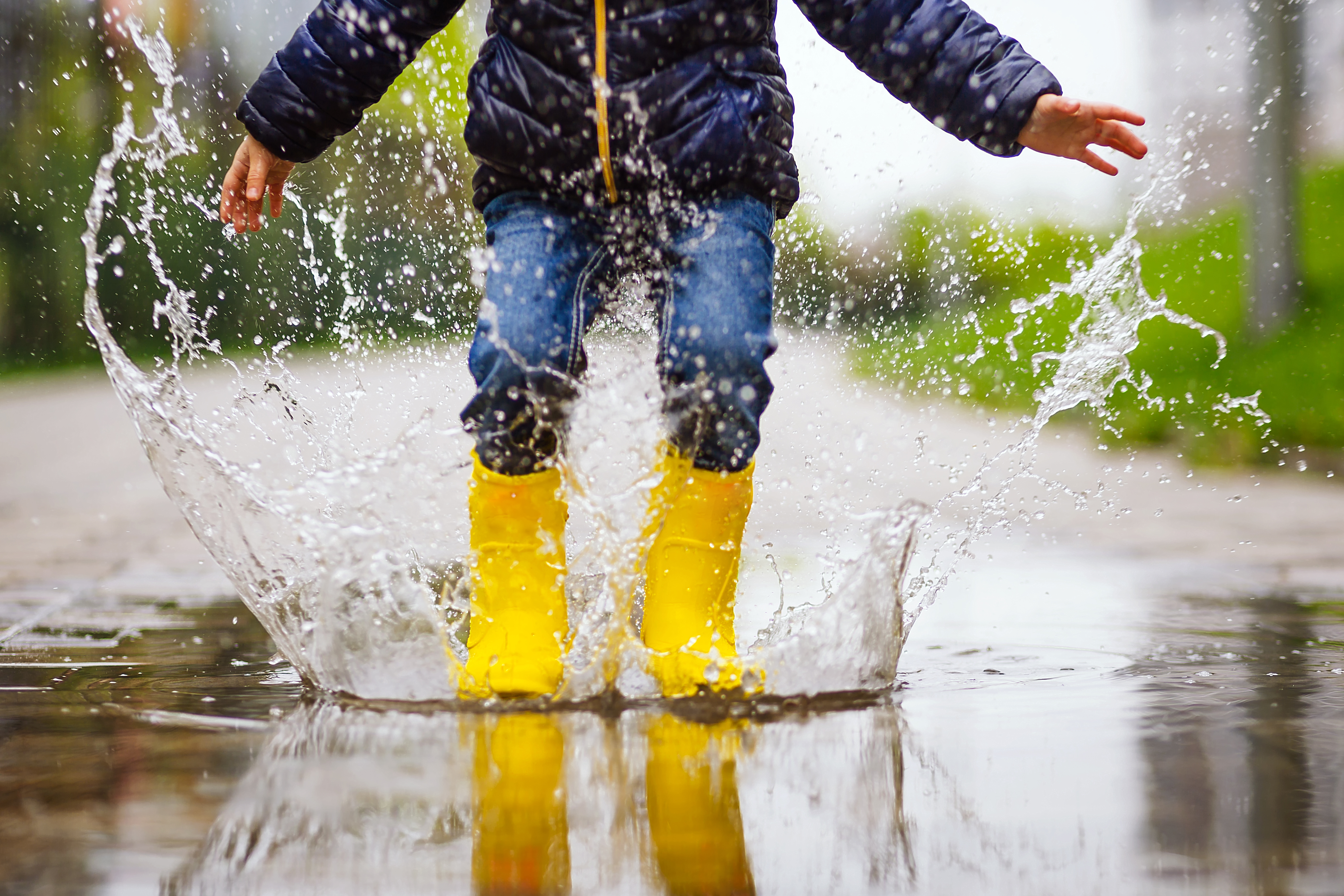 Child with rubber boots in rain